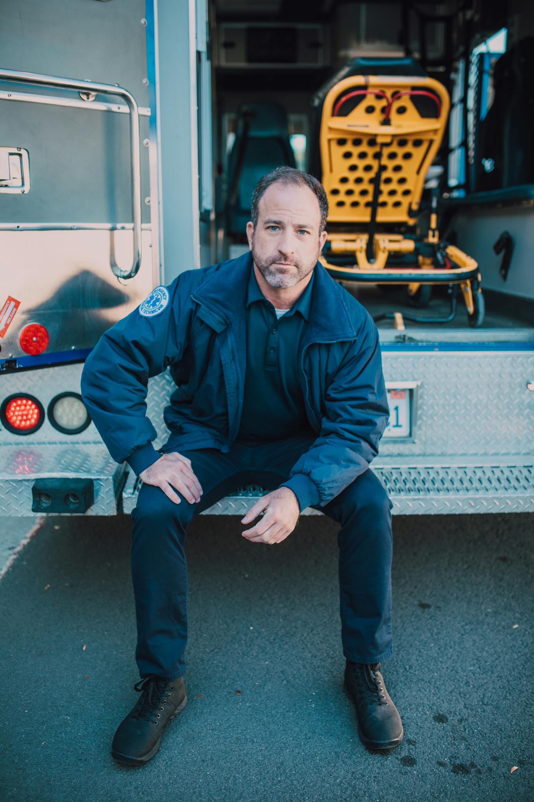 Paramedic sitting in an ambulance entrance, providing emergency medical service.